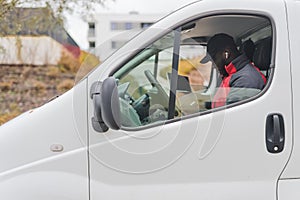 Hard-working, focused ethnic male courier during his shift. African-American man in black baseball hat sitting behind