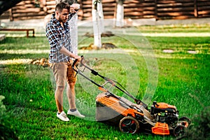 hard working gardener using lawnmower and cutting grass