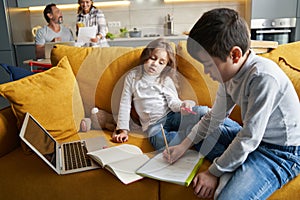 Hard-working kid preparing homework for school on couch