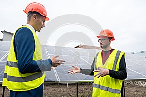 hard-working professionals in helmets and vests discuss the work process of installing panels