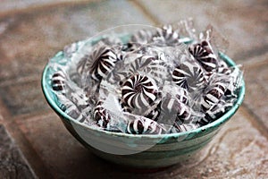 Hard wrapped licorice starlight candy in a aqua ceramic bowl.