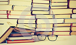 Hardback books on white wooden table, open book and glasses, copy space for text