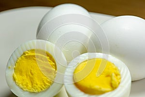 Hardboiled eggs with one cut in half on a plate at the kitchen table