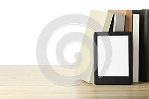 Hardcover books and modern e-book on wooden table against white background. Space for text