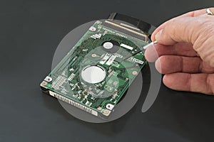 Harddrive  from a laptop computer is being inspected by a technician