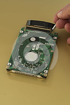 Harddrive  from a laptop computer is being inspected by a technician