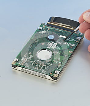 Harddrive  from a laptop computer is being inspected by a technician