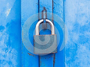 Hardened padlock hang in eye bolt on blue industrial metal door