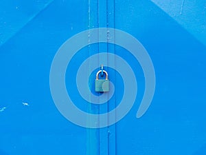 Hardened padlock hang in eye bolt on blue industrial metal door