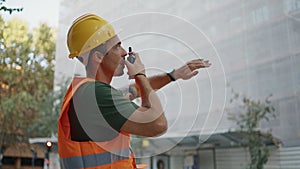 Hardhat man giving instructions using walkie-talkie in construction site closeup