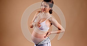 Hardships of pregnancy. Young pregnant lady suffering from backache, holding her belly and touching inflamed loins