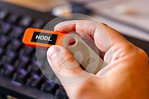 hardware Bitcoin wallet in a hand with message Hodl on screen