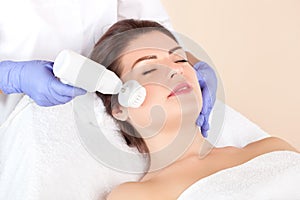 Hardware face cleaning  procedure with a soft rotating brush of a beautiful woman in a beauty salon. Cosmetology and professional