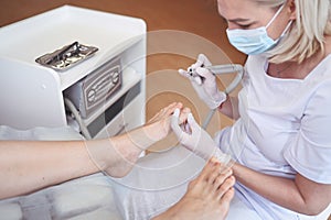 Hardware medical pedicure with nail file drill apparatus. Patient on pedicure treatment with pediatrician chiropodist. Foot