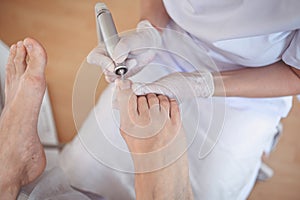 Hardware medical pedicure with nail file drill apparatus. Patient on pedicure treatment with pediatrician chiropodist. Foot