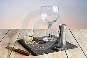 Hardware to prepare Gin Tonic with botanicals and bar spoon on wood table.