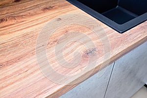 Hardwood brown textured wooden worktop and cooktop closeup in new kitchen modern stylish with sink and copyspace