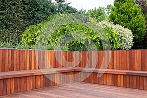 Hardwood timber deck, bench and cladding wood structure with greenery garden view, brown and green natural elements
