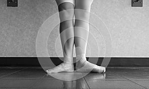 The hardworking disciplined ballerina ballet dancer warming up in her pointe shoes and bare feet, displaying the behind the scenes