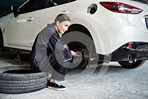 Hardworking female mechanic changing car wheel in auto repair workshop. Oxus