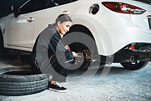 Hardworking female mechanic changing car wheel in auto repair workshop. Oxus