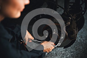 Hardworking female mechanic changing car wheel in auto repair workshop. Oxus
