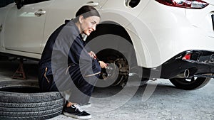 Hardworking female mechanic changing car wheel in auto repair workshop. Oxus