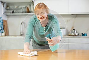 Hardworking mature woman cleaning the kitchen with cleaning products