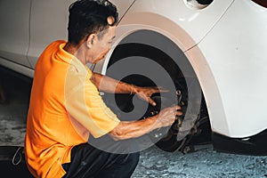 Hardworking mechanic changing car wheel in auto repair workshop. Oxus