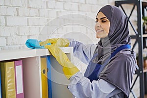 Hardworking Muslim woman cleaning the shelves in the office