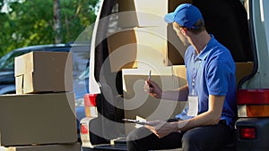 Hardworking postman counting cardboard boxes, responsible student job, inventory