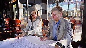 Hardworking student showing architecture project to teacher at cafe.