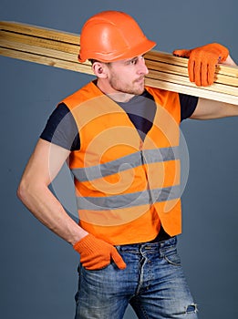 Hardy labourer concept. Carpenter, woodworker, labourer, builder on busy face carries wooden beams on shoulder. Man in