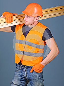 Hardy labourer concept. Carpenter, woodworker, labourer, builder on busy face carries wooden beams on shoulder. Man in