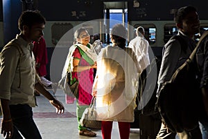HARIDWAR, INDIA - April 04, 2014 - People at railway station, indian woman in sunlight wearing sari smiling and talking.