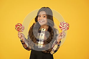 Harmful food. Crazy about sweets. Sugar addiction. Happy kid with sweet candy. Kid child holding lollipops candy yellow