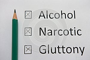 Harmful habits: alcohol, drugs, gluttony are written on white paper in pencil. Get rid of bad habits.