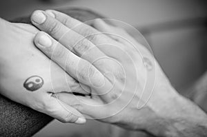 Black and white pictures. Two hands holding each other with yin and yang symbols.