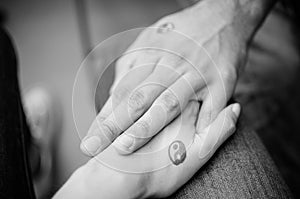 Black and white pictures. Two hands holding each other with yin and yang symbols.