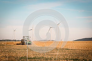 Harmonious Coexistence: Tractor Resting in Harvested Field with Wind Turbines