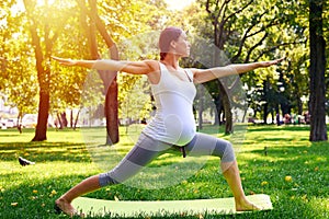 Harmonious pregnant woman meditating in yoga pose outdoors