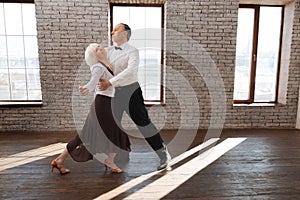 Harmonious senior dance couple dancing tango at the ballroom