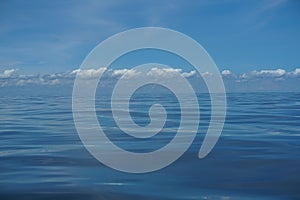 Harmony background scene of gradient blue sky horizon and low raining white cloud above deep blue sea water ripple freezing motion