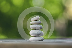 Harmony and balance, cairns, simple poise pebbles on wooden table, natural green background, simplicity rock zen sculpture