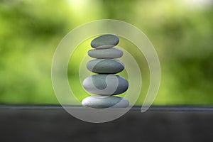 Harmony and balance, cairns, simple poise pebbles on wooden table, natural green background, simplicity rock zen sculpture