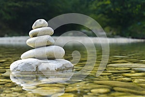 Harmony, balance and simplicity concept. A stone pyramid on the background of river water. Simple poise pebbles, rock zen