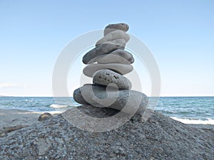 Harmony, balance and simplicity concept. A stone tower on the sea background. Simple poise pebbles, rock zen sculpture