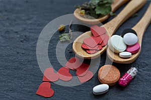 Harmony of healing with love: wooden spoons with medicinal herbs, paper hearts, and drugs