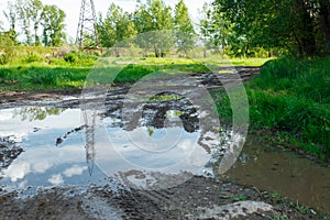 The harsh landscape nature and road through the fields for the off-road SUV with puddles and mud. Autumn or spring