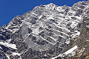 Harsh mountain structure with snow by blue sky, background picture